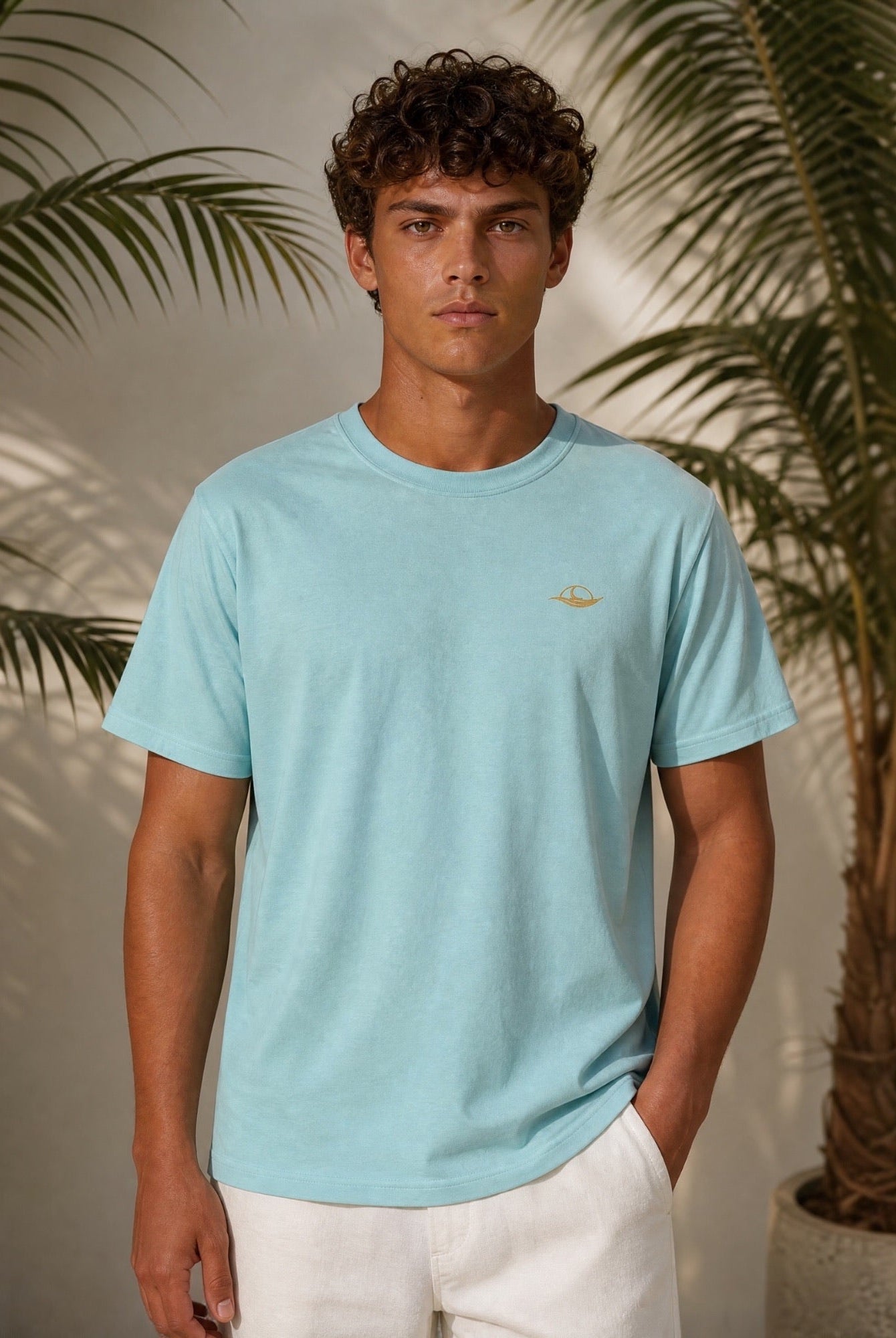 Mann in hellblauem T-Shirt mit goldenen Logo, Teil der Golden Shore Collection für Herren – T-Shirts & Hemden für Herren.