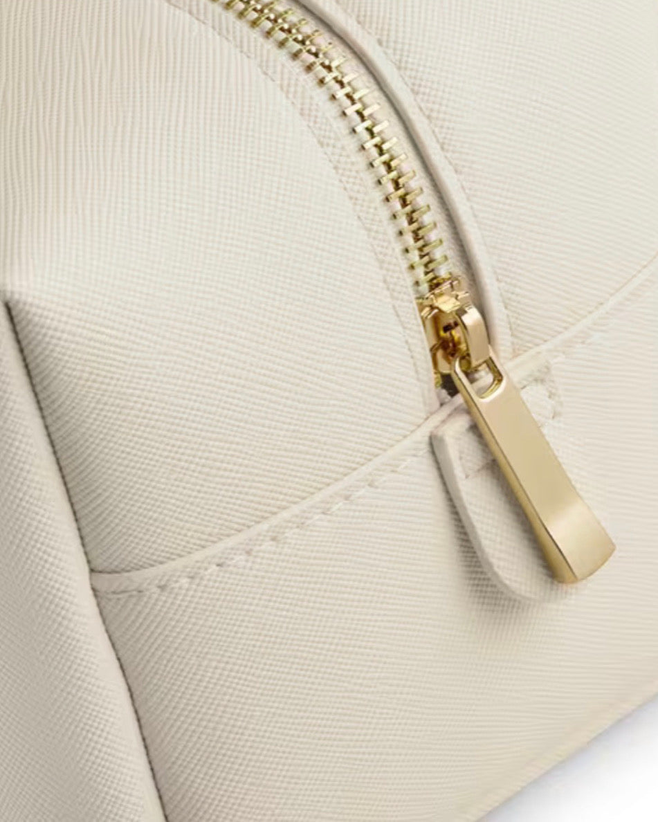 Detailansicht der Waschtasche für Damen mit goldfarbenem Reißverschluss und Saffiano-Kunstleder in Ivory.