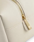 Detailansicht der Waschtasche für Damen mit goldfarbenem Reißverschluss und Saffiano-Kunstleder in Ivory.