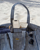Gestreifte Strandtasche mit Handy und Sonnenbrille, perfekt für den Strandtag.