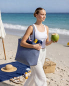 Gestreifte Strandtasche auf dem Weg zum Strand, gefüllt mit Handtüchern und einem Kokosnussgetränk.