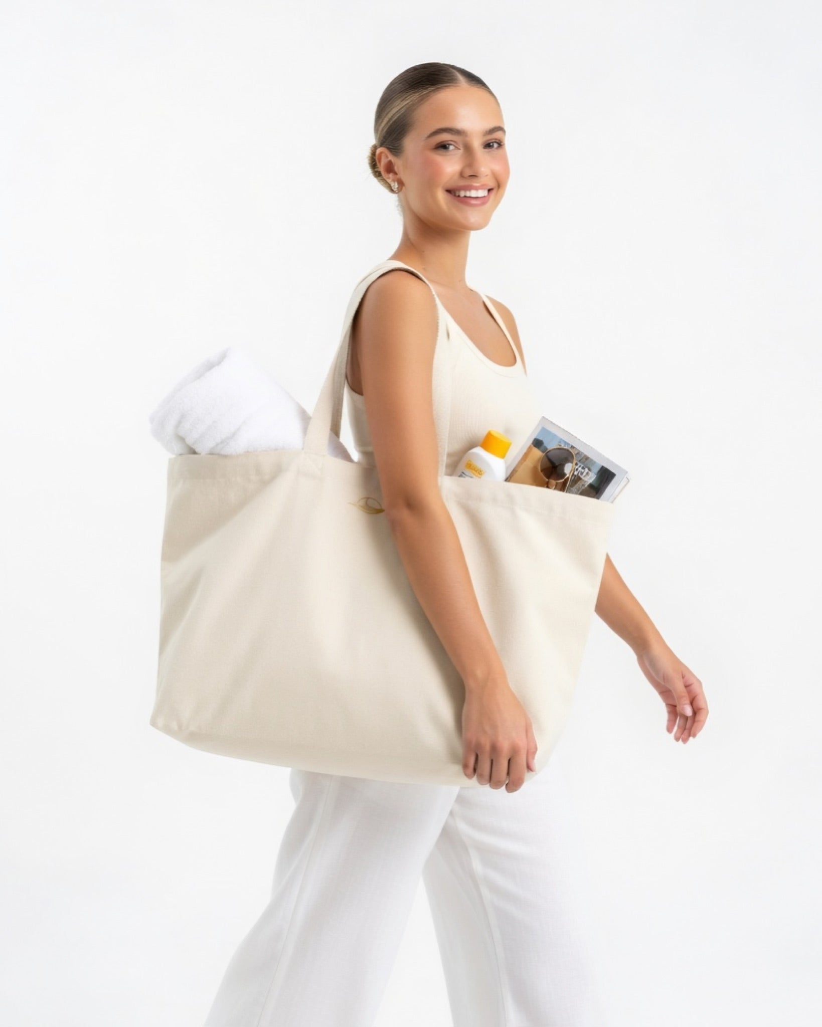 Frau mit elfenbeinfarbener Strandtasche mit goldenen Logo-Details
