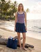 Frau am Strand mit Strandtasche, im Hintergrund Palmen, ideal für Sommeraktivitäten.
